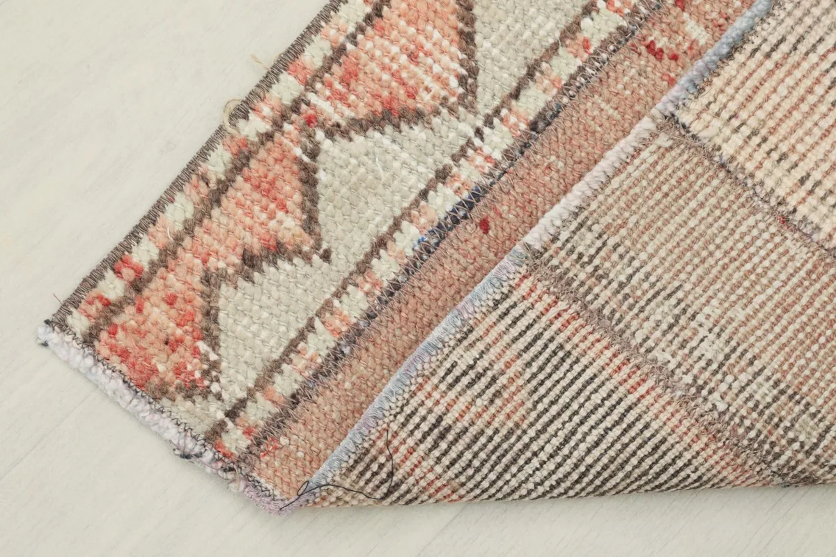 View of the rug's underside and folded edge, showing the cotton foundation and hand-knotted construction.