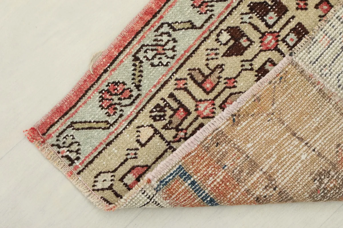 Corner of the rug folded to show the cotton foundation and hand-knotted reverse side.