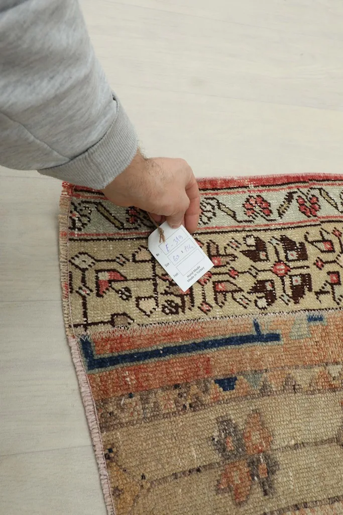 Hand holding a tag on the rug, illustrating the size and quality.