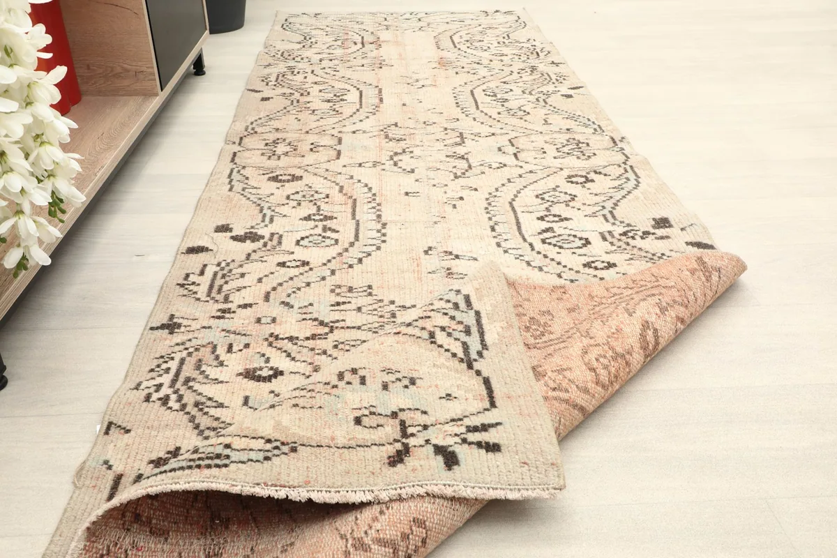 The runner partially folded, showing the reverse side and the hand-knotted construction.