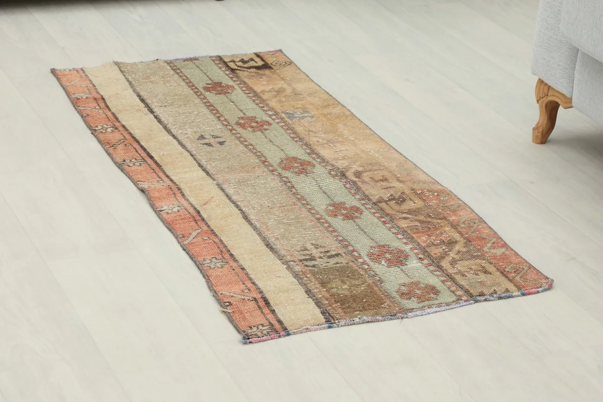 Angled view of the rust, beige, and green hand-knotted rug on a light floor