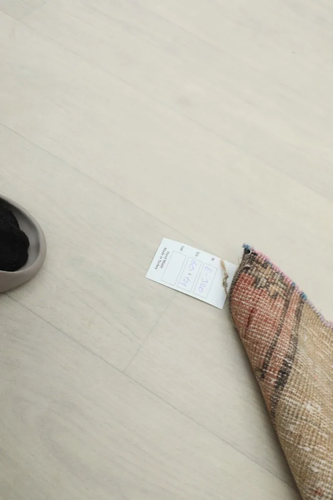 Partial view of the rug with a size tag, showing scale against a light floor