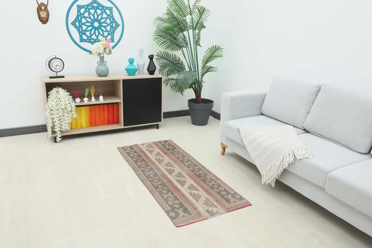 Vintage Anatolian runner rug in a modern living space with a gray sofa and plant, showing its scale.