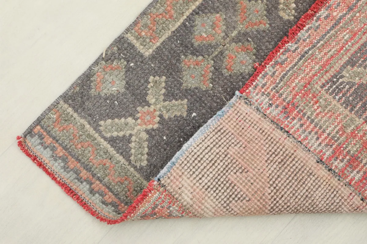 View of the rug's underside and folded corner, showing the cotton foundation and hand-knotting.