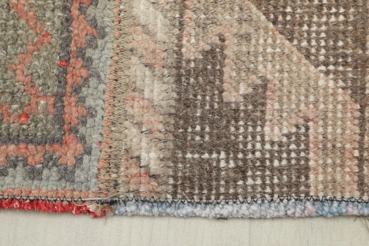 Close-up of the rug's edge, showing the red binding and the texture of the wool pile.