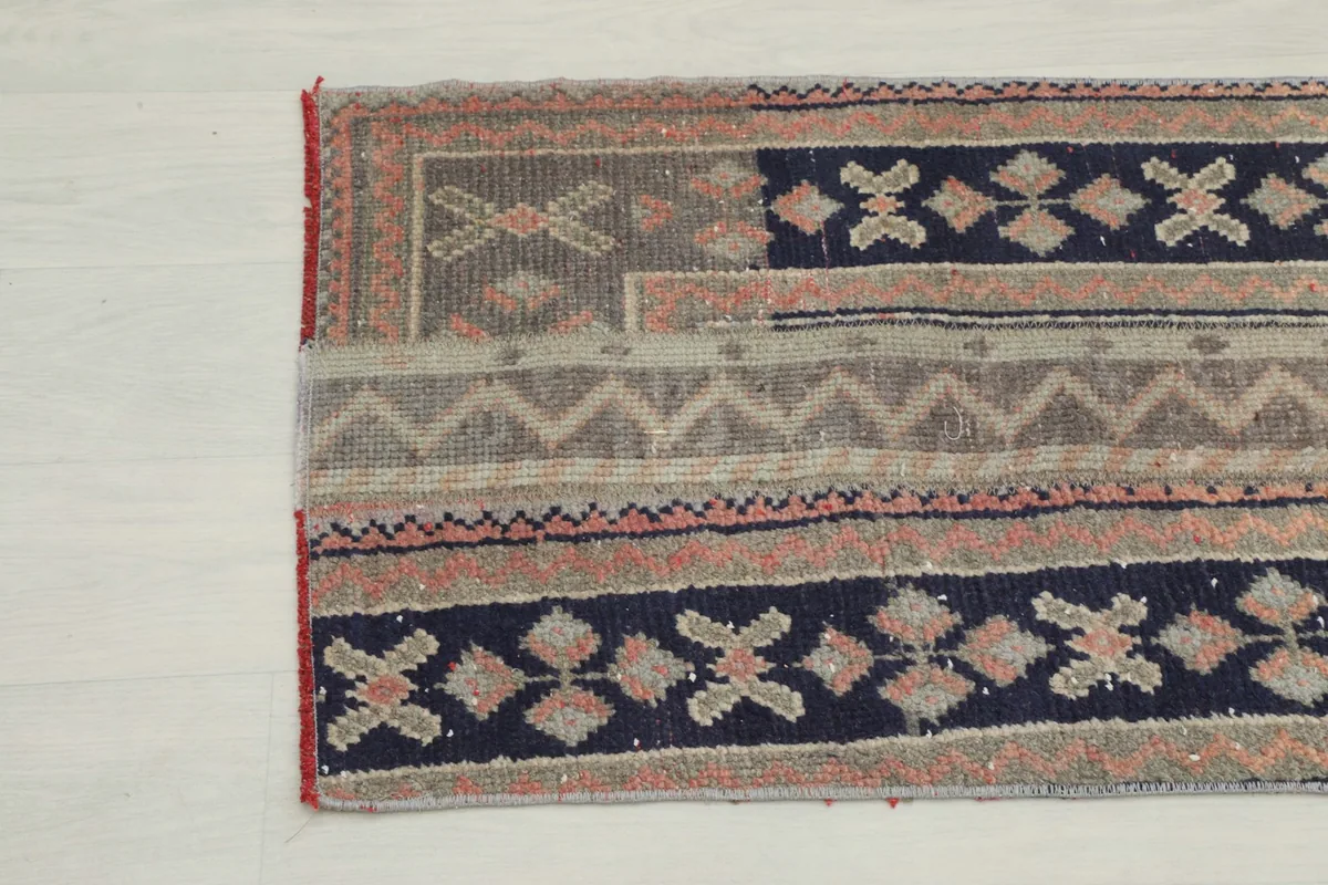 Close-up detail of the other end of the rug, featuring varied striped patterns in navy, rust, and gray