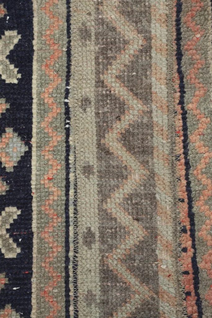 Vertical close-up showing the low wool pile and intricate hand-knotted details of the rug's patterns