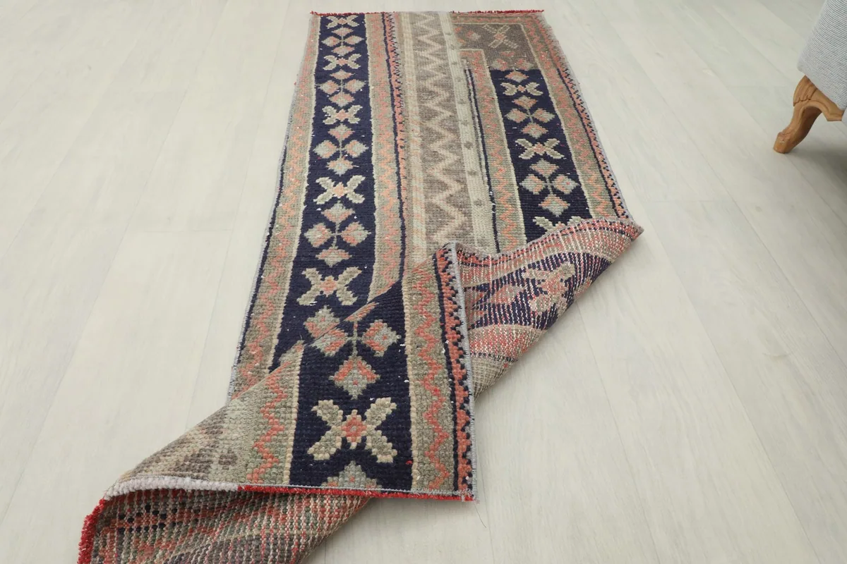 The runner rug with one end folded over, showcasing the thickness and flexibility of the vintage wool pile