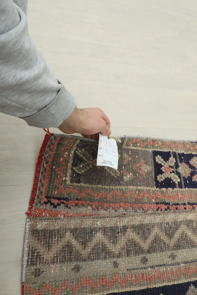 A hand holding a small tag near the rug's edge, indicating its quality and origin
