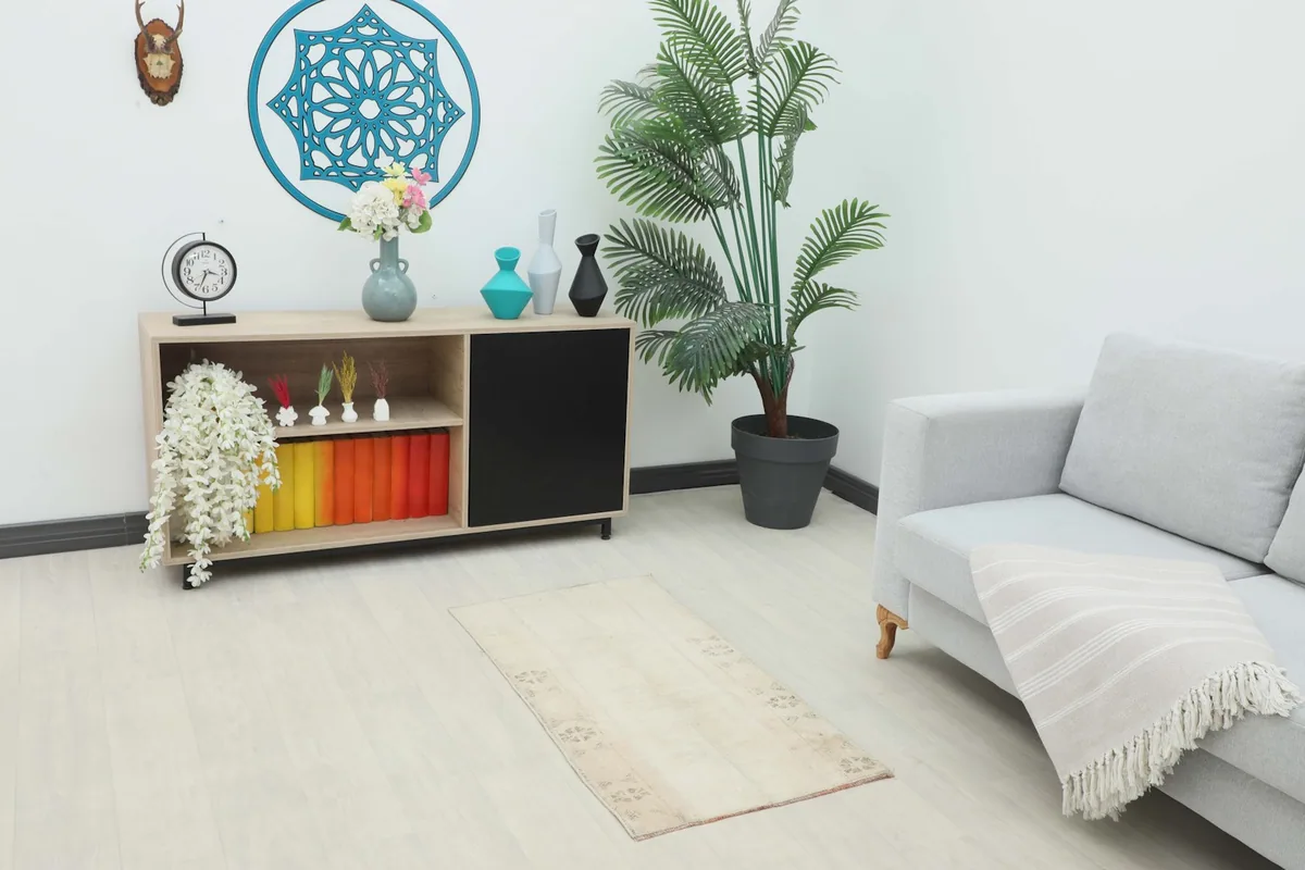 Cream vintage rug placed in a living room setting next to a sofa and cabinet