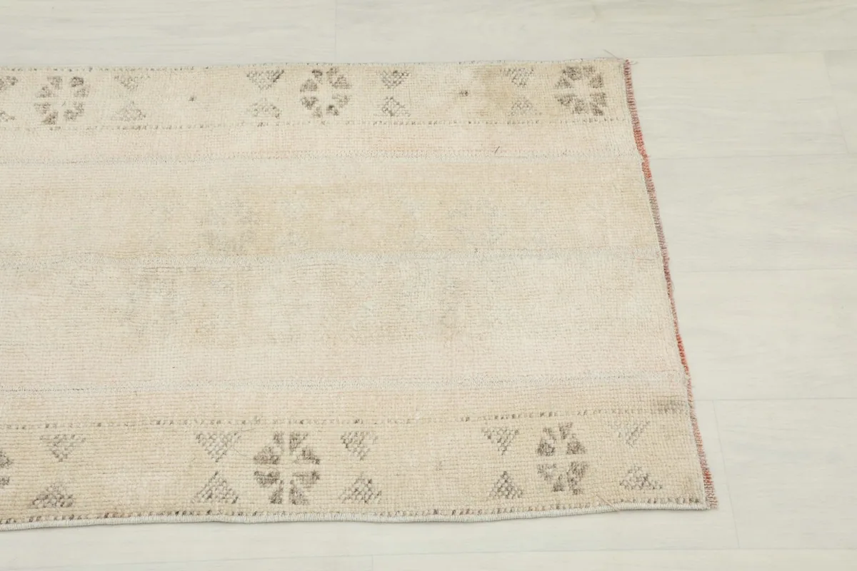 Close-up view of the upper left section of the rug showing geometric motifs and subtle color variations