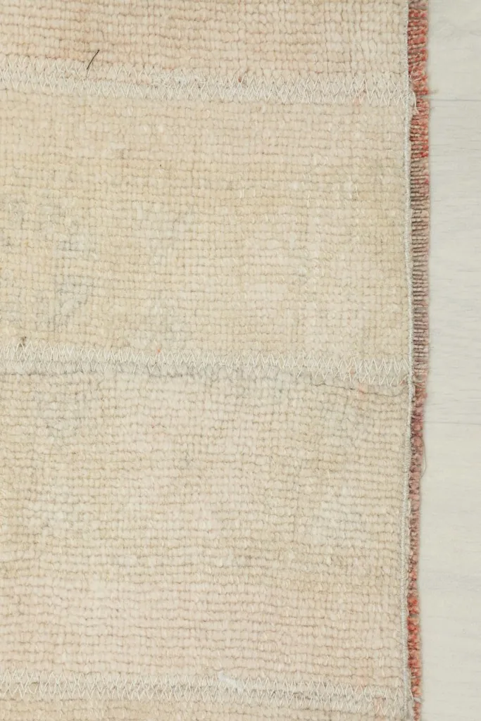 Close-up of the rug's edge, revealing the subtle red tones in the selvedge and the cotton foundation