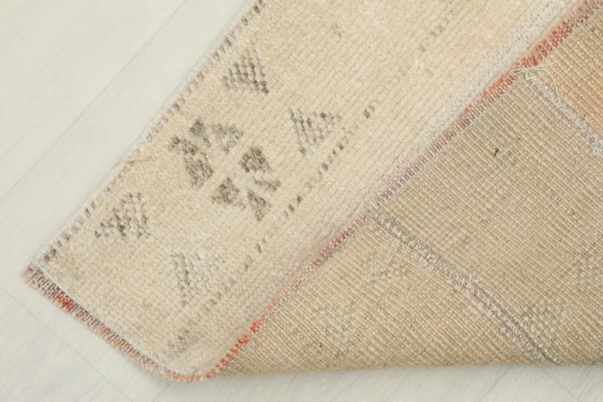 Corner of the rug folded back, showing the cotton foundation and the reverse side of the knotting