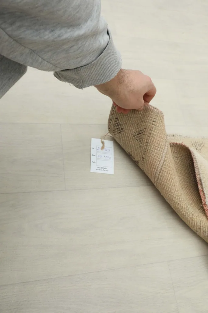 Hand holding the rug tag, showing the product information label attached to the rug