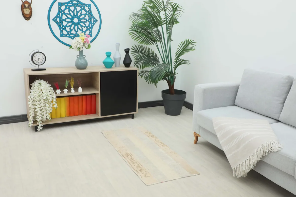 Small vintage rug placed in a living room setting under a console table and next to a sofa