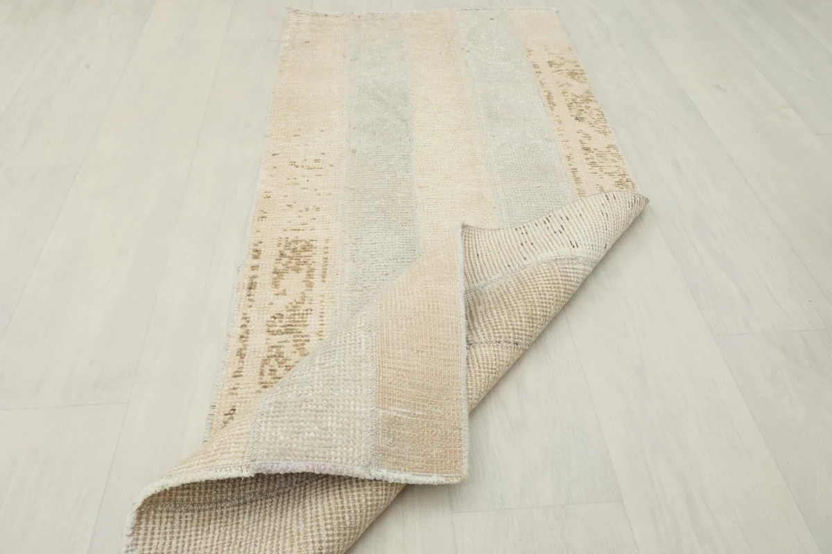 Rug partially folded, showing the distressed front and the cotton foundation