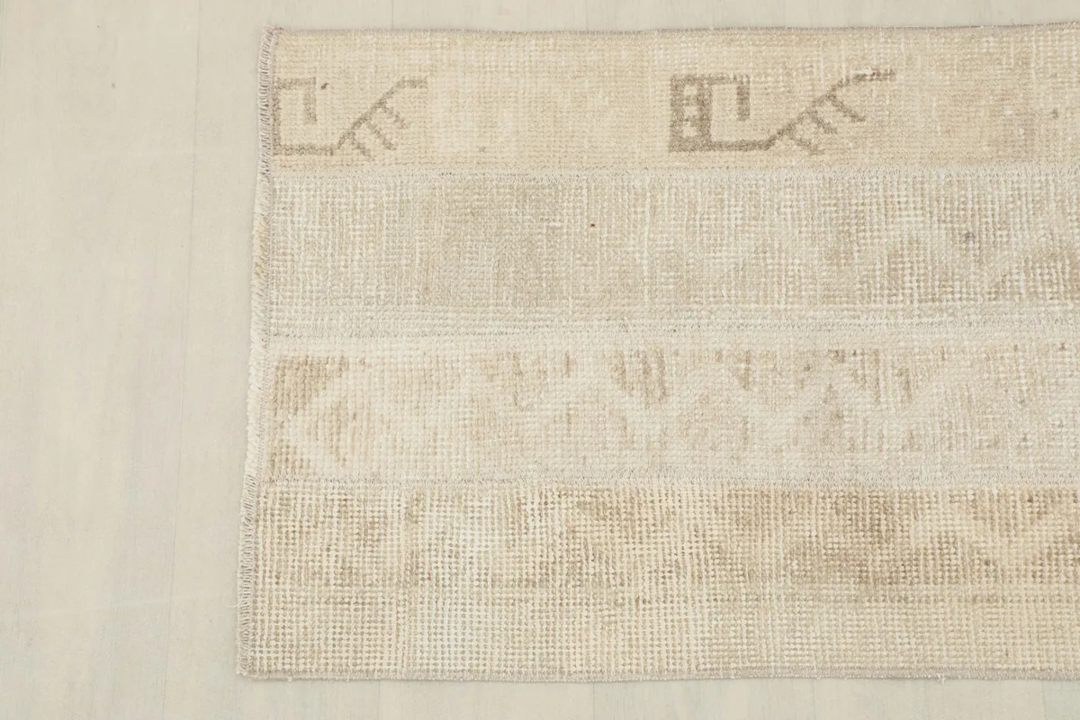 Detailed view of the upper left section of the rug, showing tribal symbols and beige tones.
