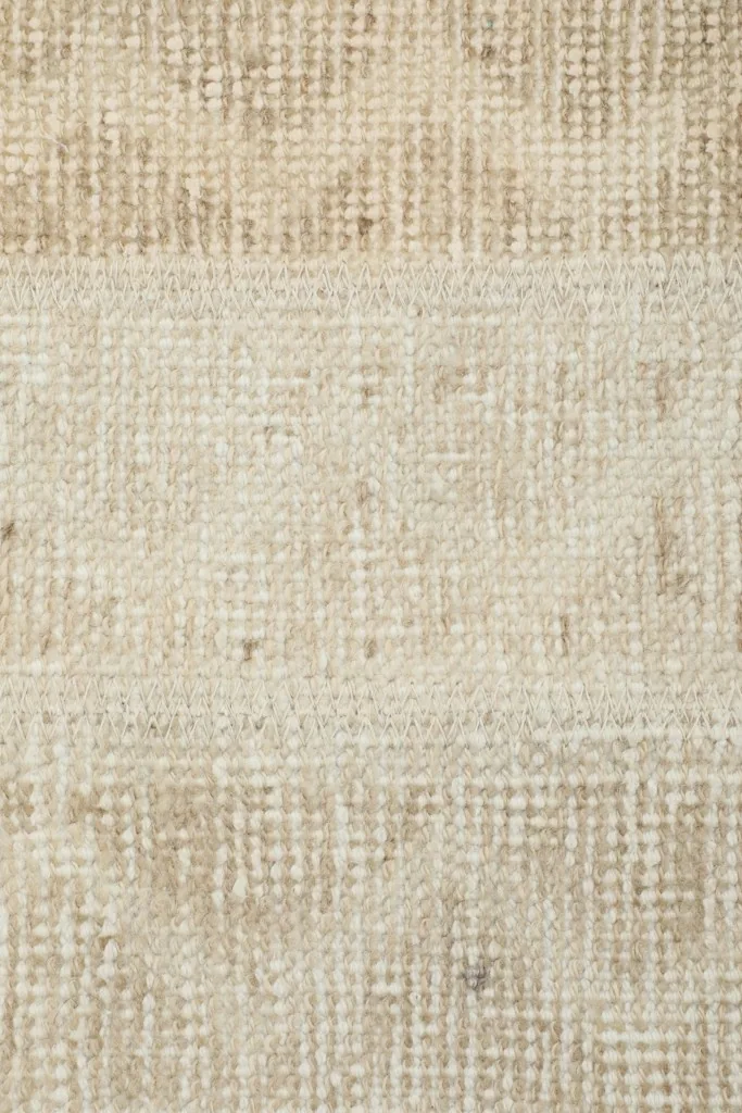 Extreme close-up of the rug's surface, showing individual knots and the distressed appearance.