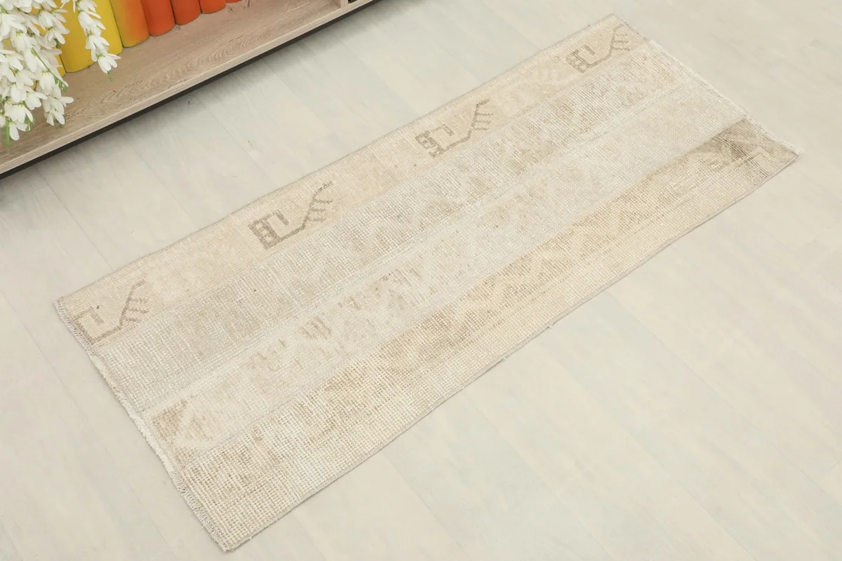 Slightly angled overhead view of the beige and tan runner rug, showing its full length and pattern.