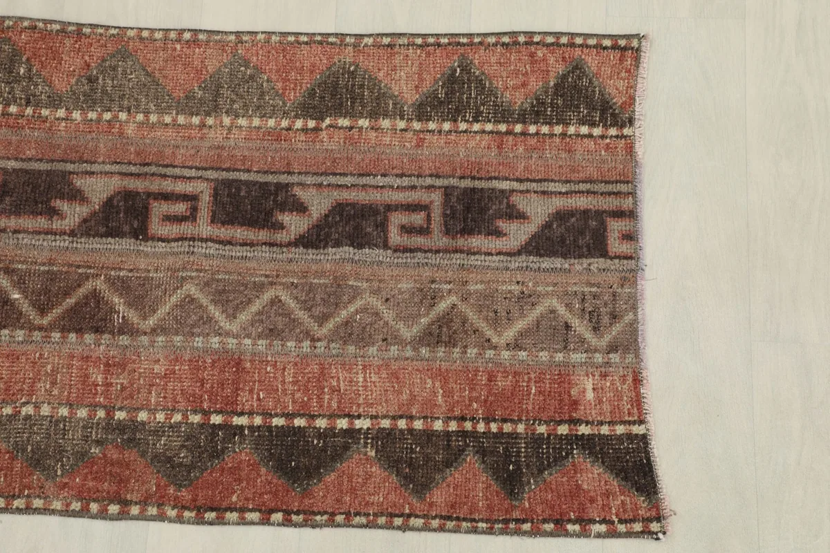 Partial view of the rug's side, featuring the repeating tribal geometric border and striped design.