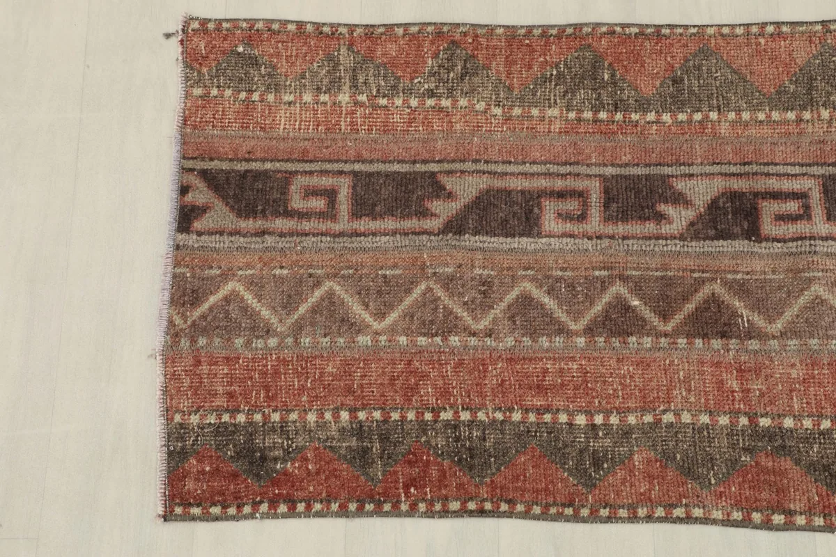 Another partial view of the rug's side, emphasizing the distinct bands of rust, brown, and beige colors.
