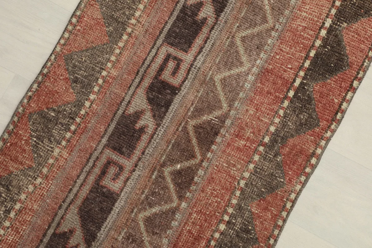 Close overhead view of the rug's central design, showing rust, brown, and beige geometric patterns.