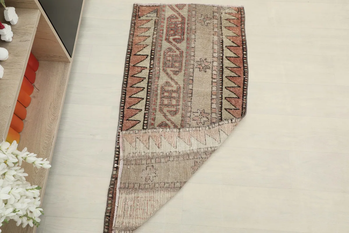The rug partially folded, displaying both the pile and the back, on a light floor