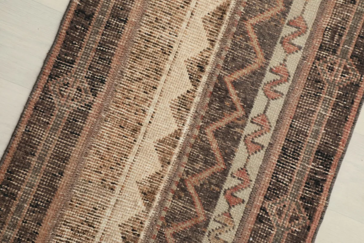 Close-up view of the rug's surface, highlighting the brown, beige, and rust geometric patterns.