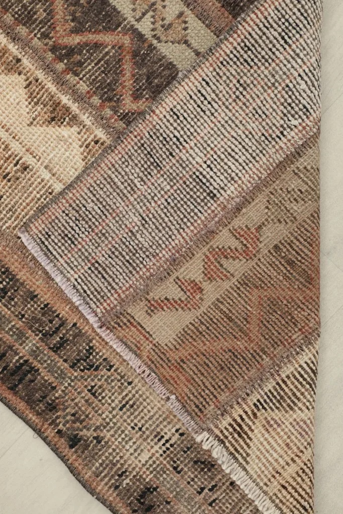 Corner view of the rug's back, revealing the hand-knotted cotton foundation and wool pile.