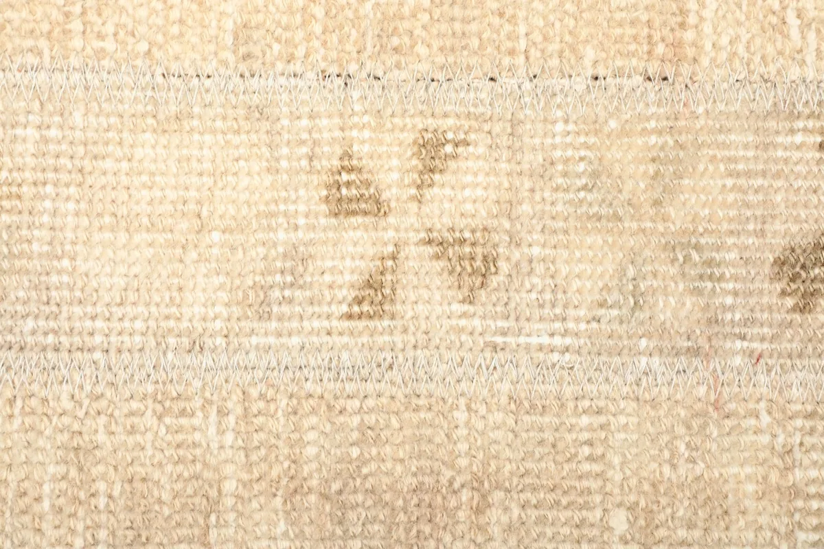 Macro shot of the low wool pile, showing the subtle variations in beige and tan tones