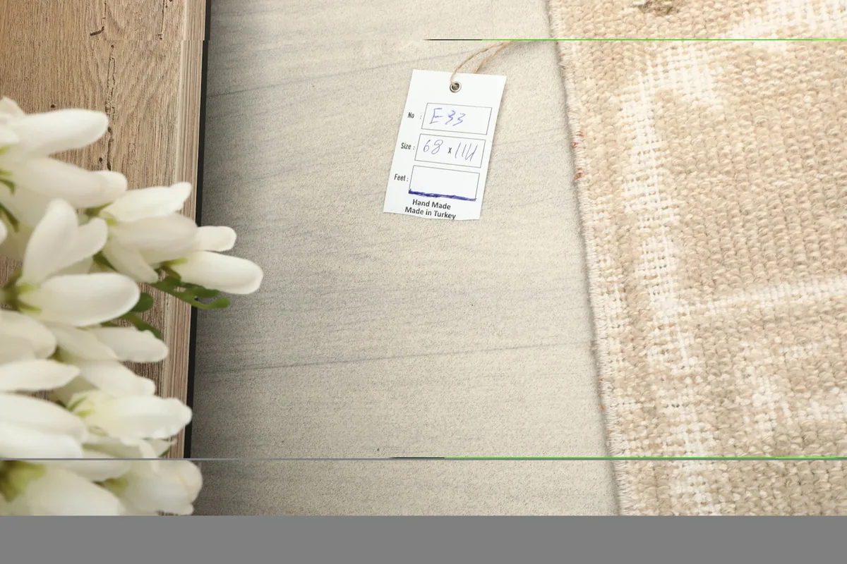 A tag with rug dimensions and origin, placed next to the rug on a light wooden surface