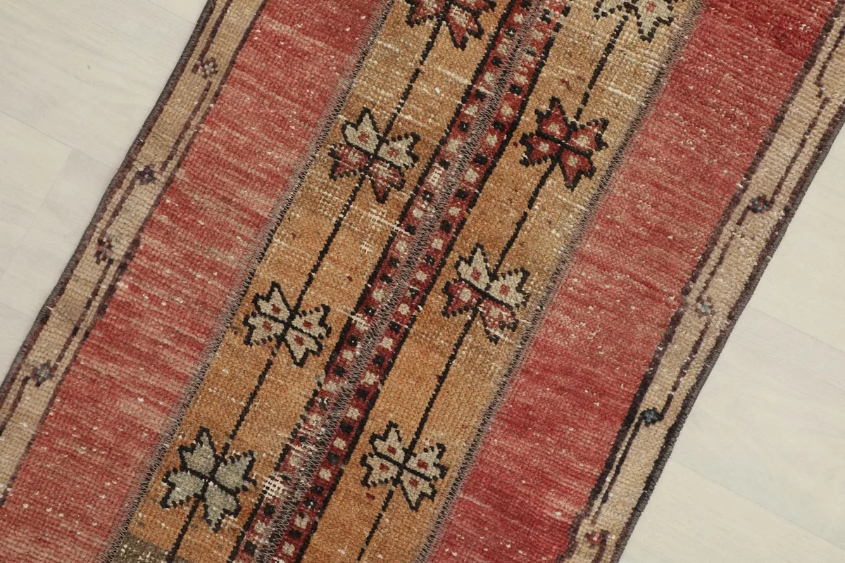 Close-up detail of the rose, tan, and brown striped sections with black geometric motifs