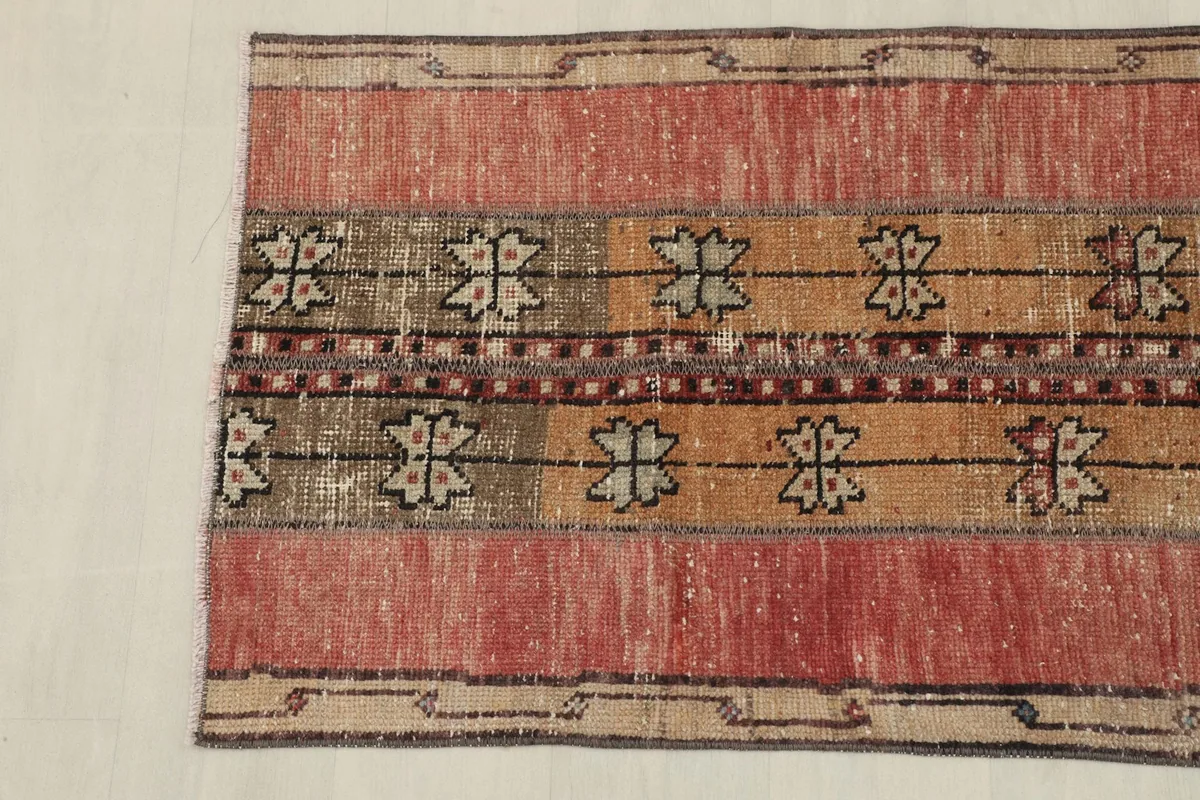 Close-up of the rug's short end, showing the faded rose field and a subtle tan border design