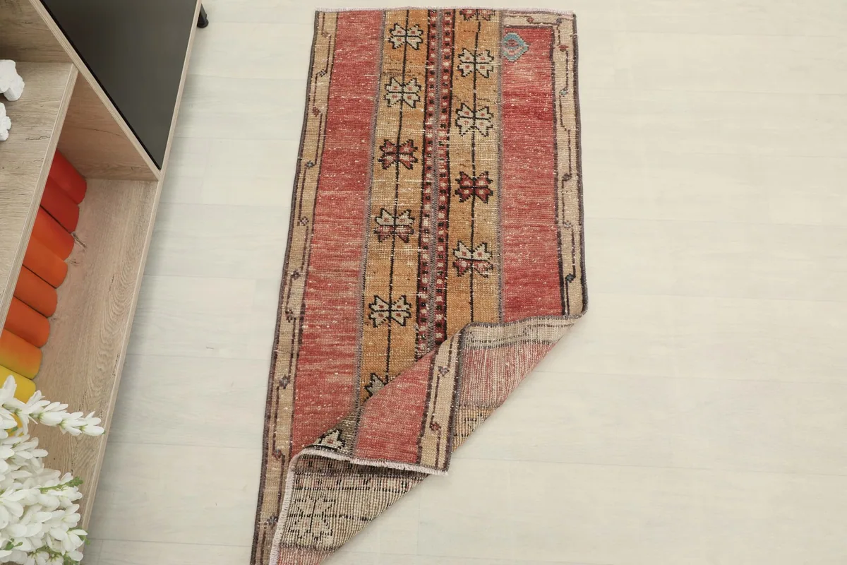 The rug partially folded, showing its flexibility and the reverse side, next to a shelf