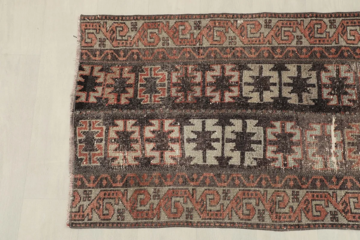 Detailed image of the rug's patterns and colors, focusing on the interplay of charcoal, rust, and tan