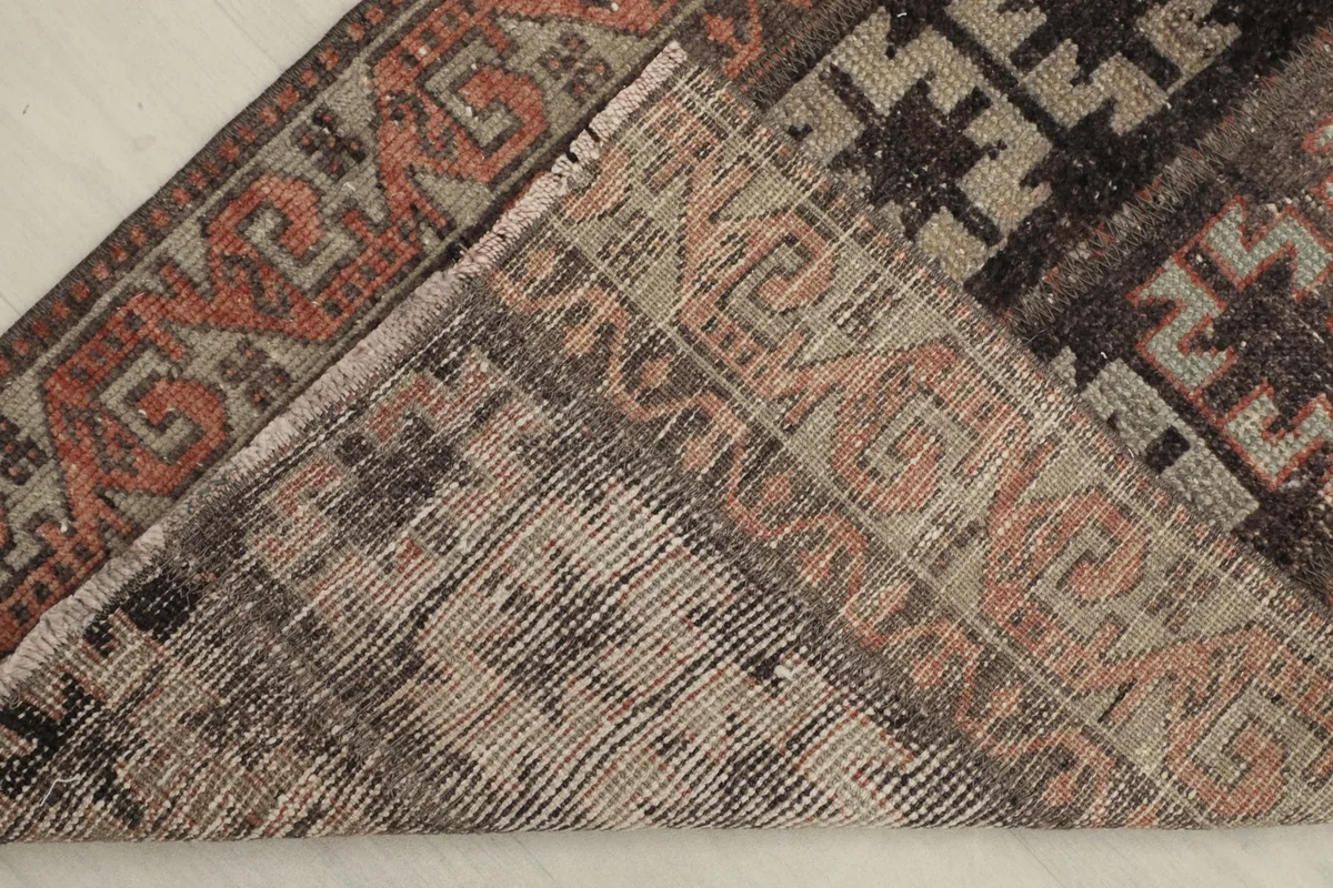 View of the back of the rug, folded to show the cotton foundation and hand-knotted construction