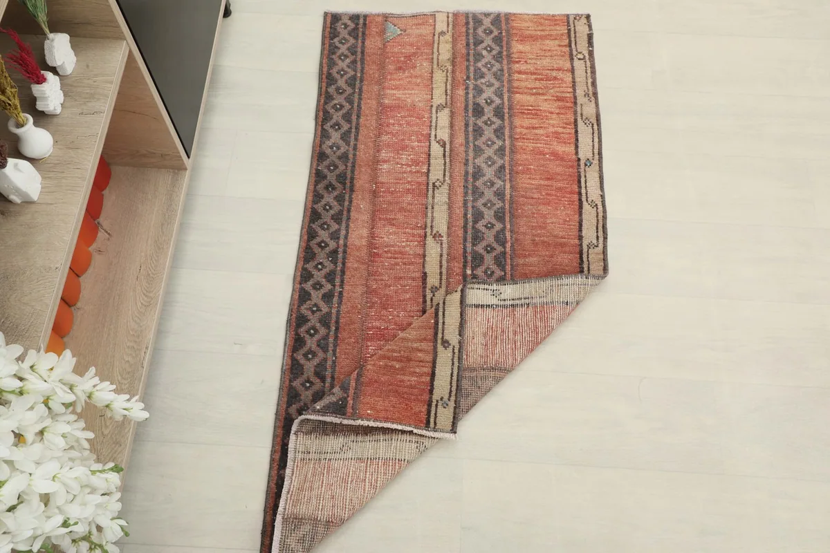 The rust striped rug partially folded, showing its size and decorative potential in a home setting.