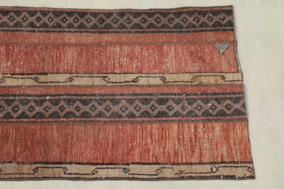 Close-up detail of the rug's rust field and charcoal geometric striped pattern.