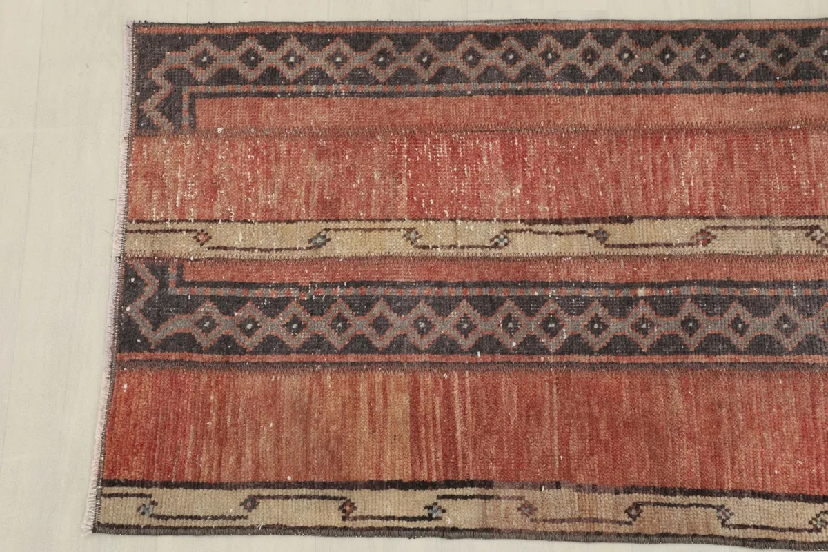 Detailed shot of the corner of the rug, highlighting the geometric motifs and color variations.