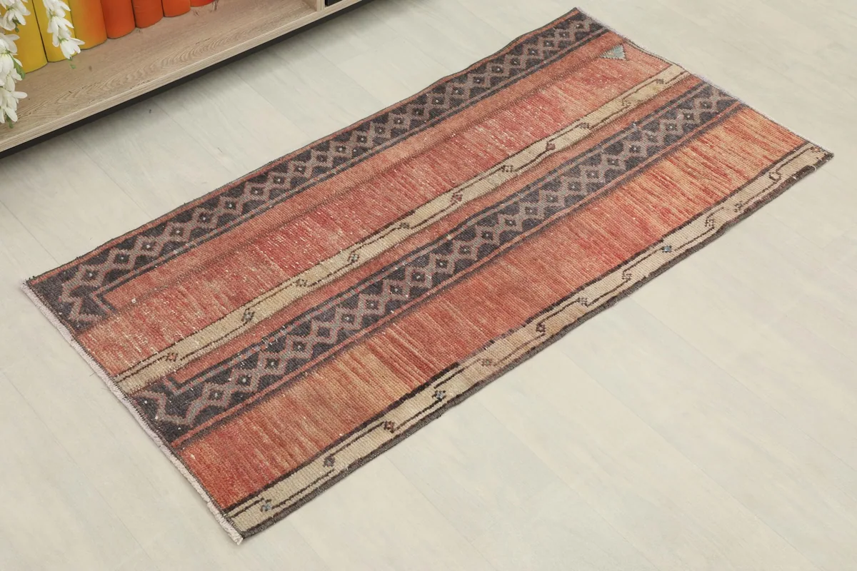 Overhead angled view of the rust, charcoal, and beige vintage area rug, showing its striped pattern.