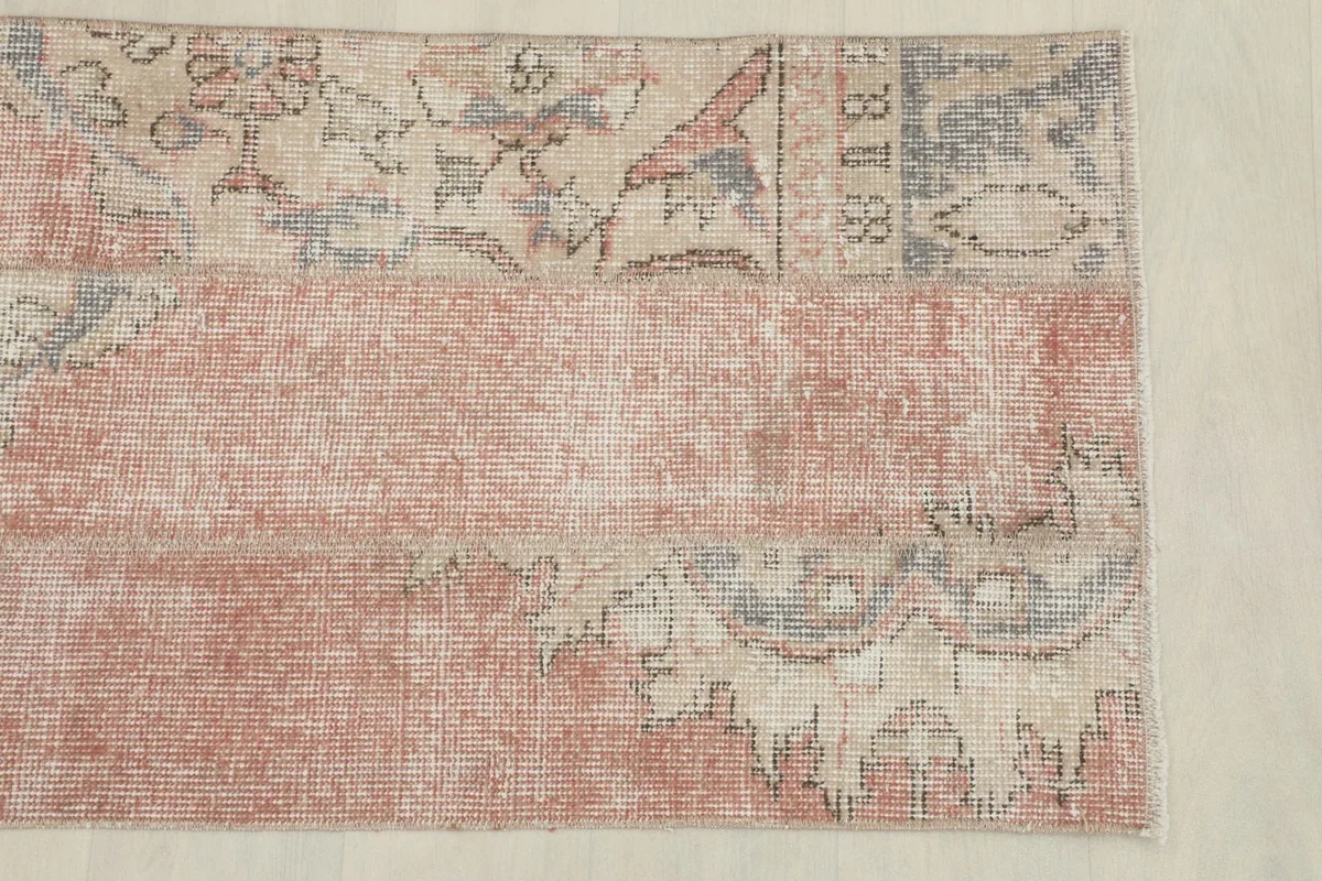 Detailed view of the upper section of the rug, showing floral and geometric patterns on a beige ground.