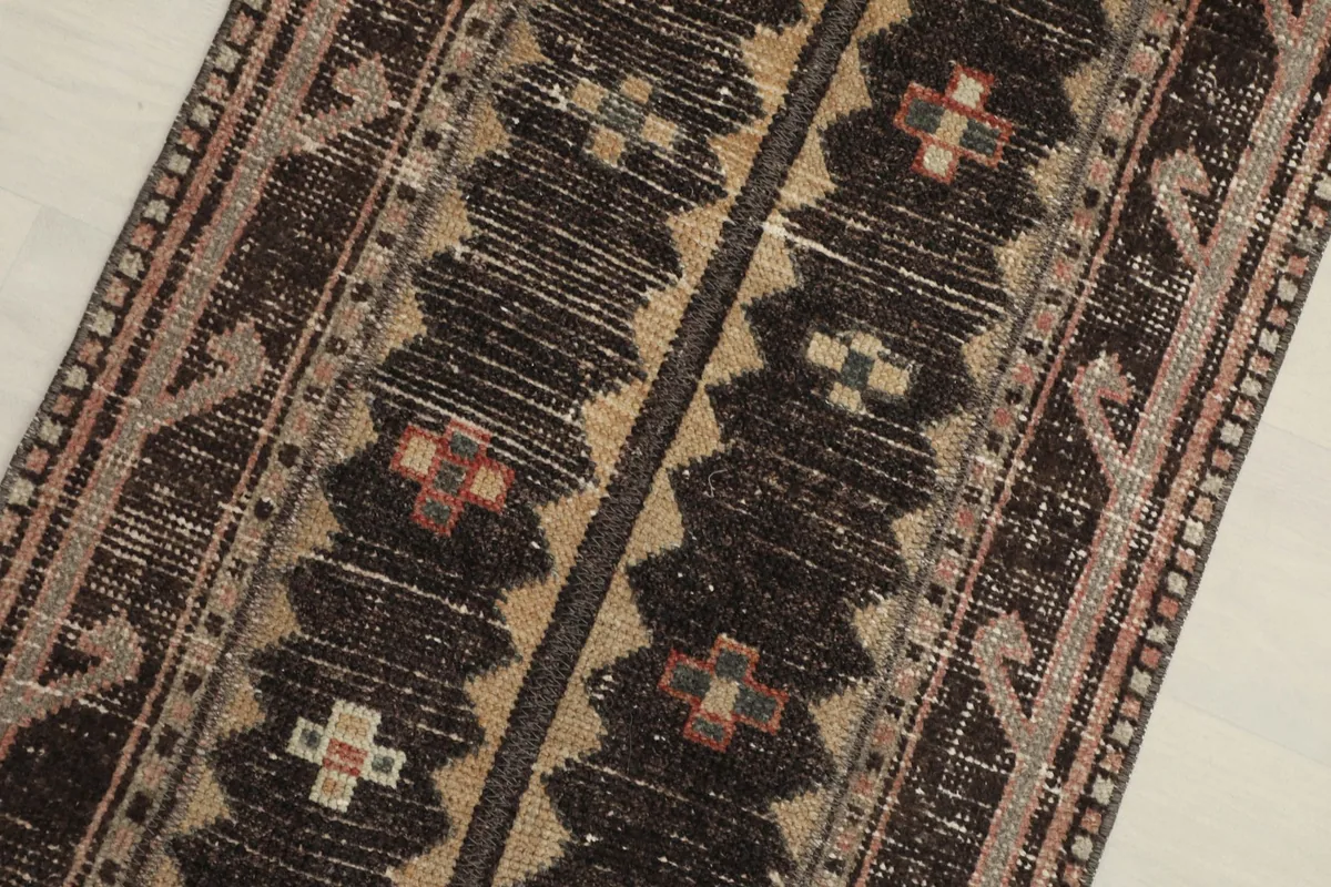 Close-up detail of the charcoal and tan field with distinct geometric motifs and subtle rose and olive accents.