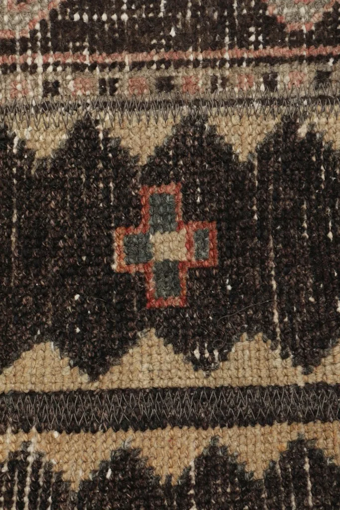 Macro detail of a central geometric motif, highlighting the knotting and color variations including green and red.