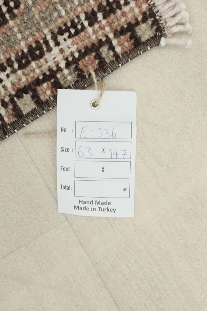 Close-up of the rug's product tag, confirming its hand-made origin and dimensions in centimeters.
