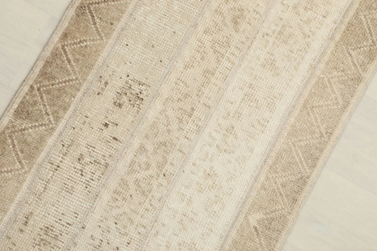 Close-up detail of the rug's beige and tan geometric patterns and texture.