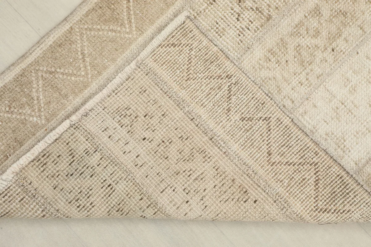View of the back of the hand-knotted wool rug, revealing its cotton foundation and knotting.