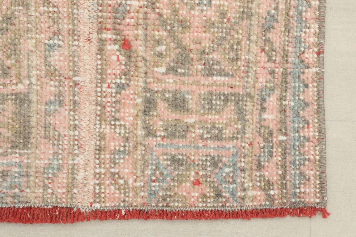 Edge detail of the runner, showing the pattern extending to the border and the short red fringed ends.