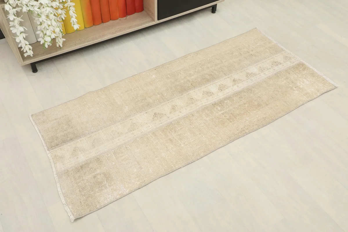 Angled view of the vintage tan Anatolian runner, showing its full length and geometric pattern.