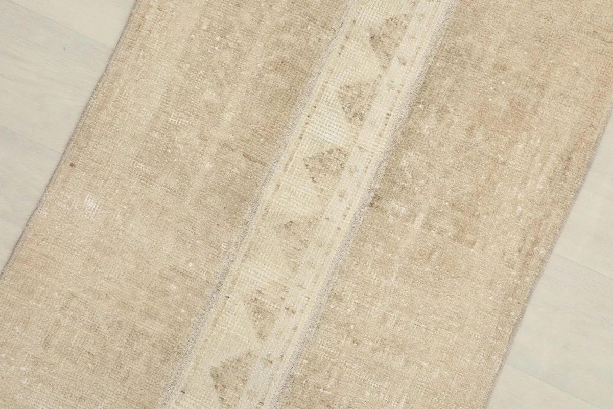 Close-up detail of the central geometric pattern in beige tones on the tan vintage runner.
