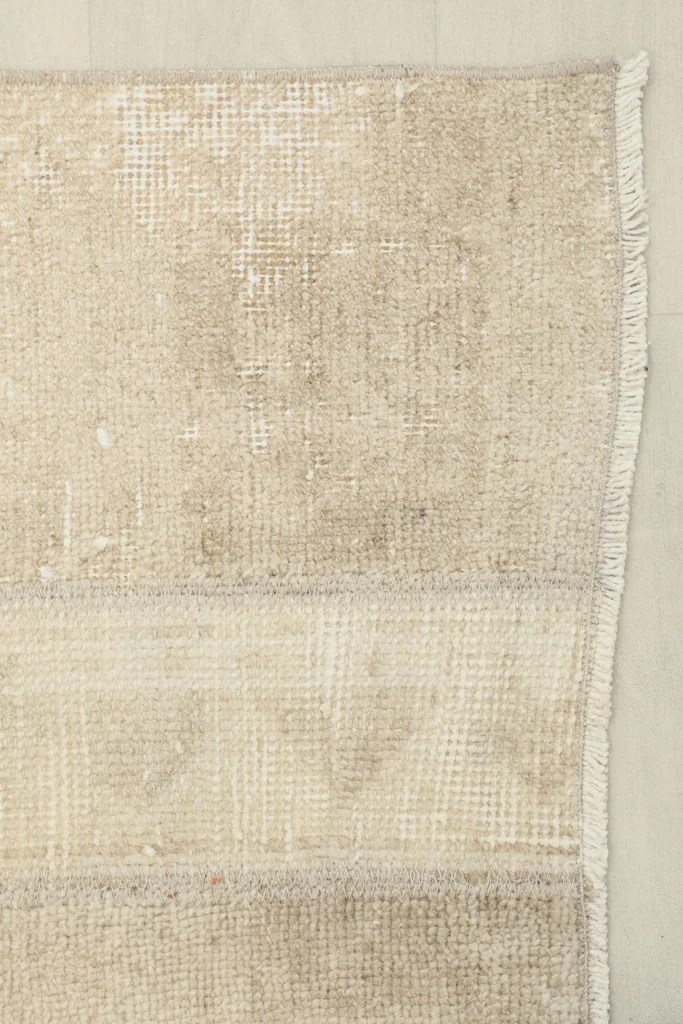 Close view of the low wool pile and subtle color variations at the edge of the vintage runner.